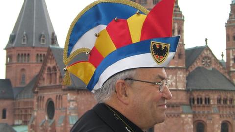 Kardinal Karl Lehmann im Jahr 2004 mit der Ehrenmütze des Aachener Karnevalsvereins auf dem Kopf vor dem Mainzer Dom.