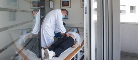 Ein Arzt behandelt eine Long-Covid-Patientin, die auf einer Liege liegt.