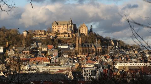 Das Marburger Schloss und darunter die Altstadt vor bewölktem Himmel