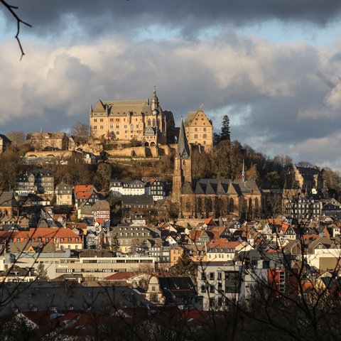 Das Marburger Schloss und darunter die Altstadt vor bewölktem Himmel