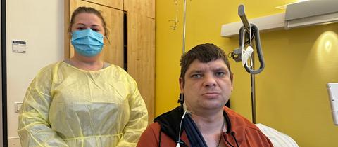 Eine Frau steht mit Kittel und Mundschutz neben einem Mann in einem Marburger Krankenhaus