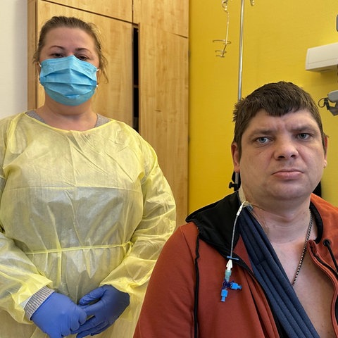 Eine Frau steht mit Kittel und Mundschutz neben einem Mann in einem Marburger Krankenhaus