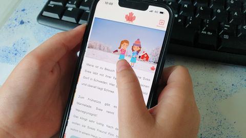 Kind scrollt durch Text: Kinderhände halten ein Smartphone