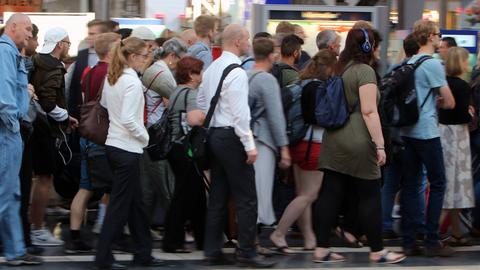 Viele Menschen drängen sich auf einem Bahnsteig und laufen zum Ausgang. 