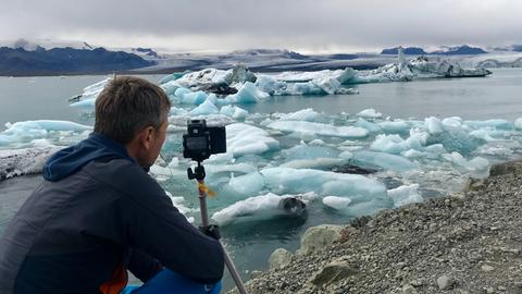 Michael Gutsche mit Kamera vor einem Gletscher.