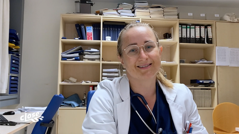 Stefanie Minkley sitzt mit Arztkittel in einem Büro ihrer Klinik.