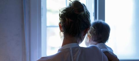 Eine Mutter und ein Baby blicken aus einem Fenster.