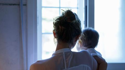 Eine Mutter und ein Baby blicken aus einem Fenster.