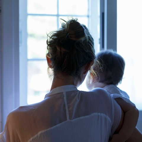Eine Mutter und ein Baby blicken aus einem Fenster.