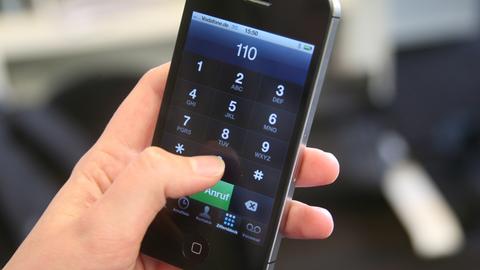 Hand wählt auf dem Smartphone den Notruf 110