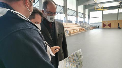 drei Männer blicken auf einen Plan