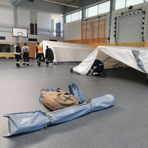 Zelte, die in einer Turnhalle aufgebaut werden