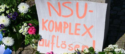 "NSU-Komplex auflösen" steht auch einem Karton, der inmitten das Blumenmeer an einem Gewdenkort gestellt wurde.