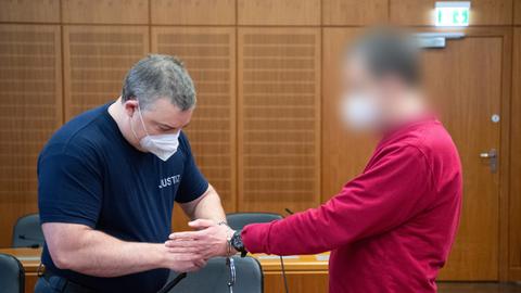 Angeklagter bekommt von einem Justizbeamten im Gerichtssaal Handschellen abgelegt.