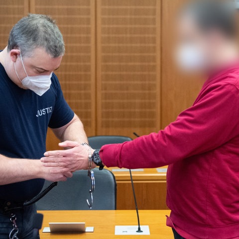Angeklagter bekommt von einem Justizbeamten im Gerichtssaal Handschellen abgelegt.