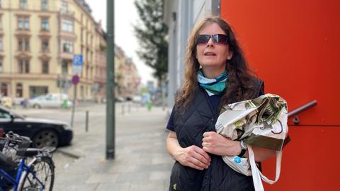 Bettina arbeitet seit zehn Jahren als Streetworkerin. Frau mit Sonnenbrille, in schwarz gekleidet steht mit einer schwarzen Umhängetasche im Frankfurter Bahnhofsviertel.
