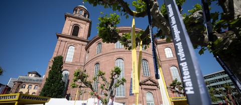 Vor der Paulskirche in Frankfurt sind Bäume mit bunten Bändern geschmückt.