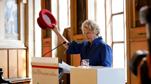 Petra Roth zieht in der Frankfurter Paulskirche symbolisch den Hut.