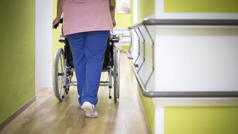 Pflegerin schiebt Heimbewohner im Rollstuhl