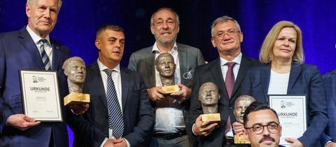 Die Preisträger des Hamza-Kurtović-Awards stehen in einem Gruppenbild für die Presse zusammen und lächeln mit ihren Urkunden und Skulpturen in den Händen in die Kamera.