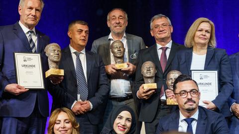 Die Preisträger des Hamza-Kurtović-Awards stehen in einem Gruppenbild für die Presse zusammen und lächeln mit ihren Urkunden und Skulpturen in den Händen in die Kamera.