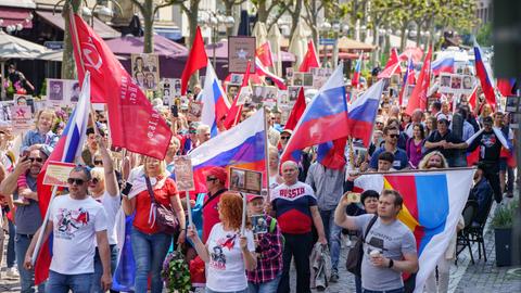 Mit russischen Fahnen und solchen der untergegangenen UdSSR sind etwa 300 Menschen bei einer pro-russischen Demonstration in Frankfurt unterwegs. 