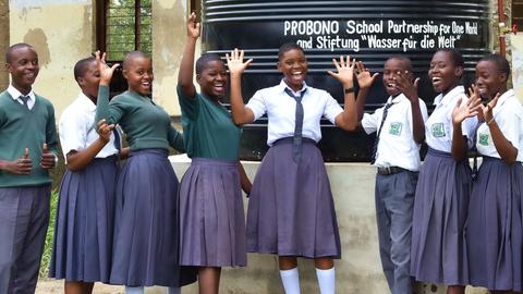Mädchen stehen vor einem Wassertank an der Kiluvya Seconday School, Tansania, März 2020