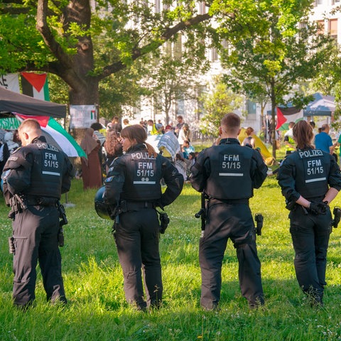 Plizisten beobachten Teilnehmende des propalästinensisches Protestcamp