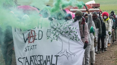 Umweltaktivisten protestieren im Dannenröder Forst mit einem Transparent und einer Rauchfackel gegen den A49-Ausbau