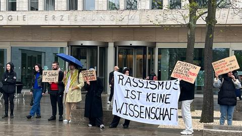 Menschen protestieren mit Schildern, auf denen "Rassismus ist keine Wissenschaft" steht, gegen eine Tagung an der Frankfurter Goethe-Universität