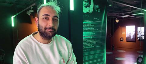 Der iranische Flüchtling Alan Farazi steht im Techno-Museum Momem an einem Plattenspieler vor einem Plakat über den japanischen DJ Ken Ishii