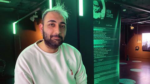 Der iranische Flüchtling Alan Farazi steht im Techno-Museum Momem an einem Plattenspieler vor einem Plakat über den japanischen DJ Ken Ishii