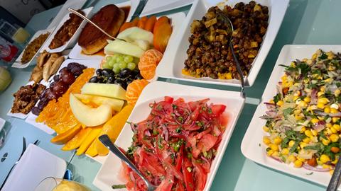 Ein reichlich gedeckter Tisch: Salate, Datteln, Samosa, Hühnchen sind zu sehen.