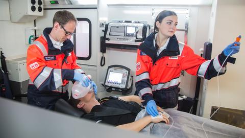 Ein Mann und eine Frau beatmen einen Patienten im Rettungswagen