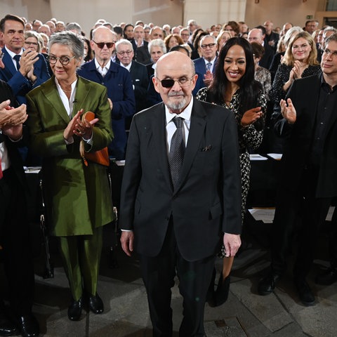 Der britisch-indische Autor Salman Rushdie (M) bekommt zu Beginn der Verleihung des Friedenspreis des Deutschen Buchhandels in der Paulskirche stehenden Applaus.