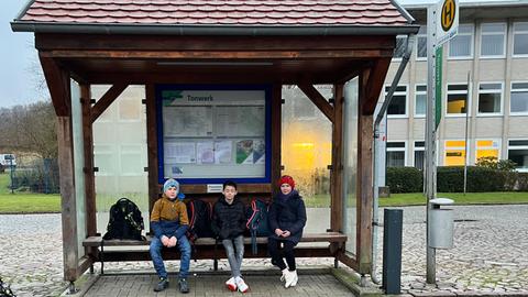 Isabell sitzt mit ihren Schulfreunden Moritz und Jannis auf einer Bank an der Bushaltestelle in Rommerode