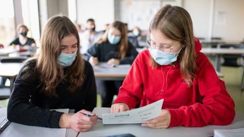 Zwei Schülerinnen mit OP-Masken im Unterricht. 