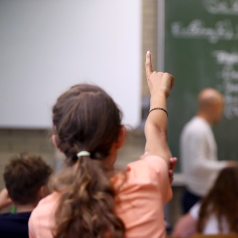 Ein Mädchen meldet sich im Schulunterricht.