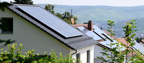 Dächer mit Solaranlagen auf Häusern an einem Hang. 