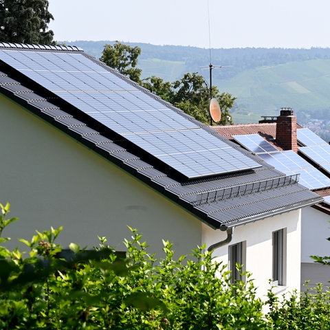 Dächer mit Solaranlagen auf Häusern an einem Hang. 