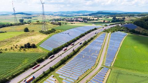 Das Foto zeigt Solaranlagen-Flächen neben einer Autobahn - aus der Vogelperspektive.