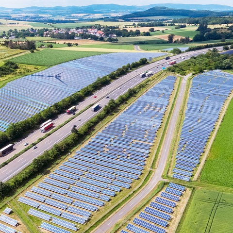 Das Foto zeigt Solaranlagen-Flächen neben einer Autobahn - aus der Vogelperspektive.