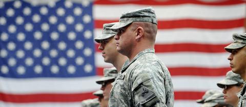 US-Soldaten in Tarnkleidung vor der US-Flagge