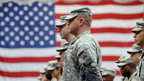 US-Soldaten in Tarnkleidung vor der US-Flagge