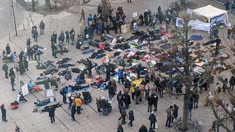 Demonstranten der Liegendemo haben sich zu Protestzwecken auf den Boden eines Platzes in Stuttgart gelegt.