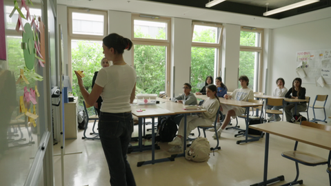 Es ist eine Schulklasse im Klassenzimmer zu sehen