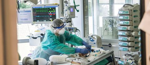 Eine Pflegerin kümmert sich auf einer Intensivstation um eine Patientin