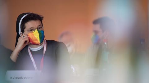Eine Teilnehmerin mit Regenbogen-Maske sitzt zu Beginn der Dritten Synodalversammlung der deutschen Katholiken an ihrem Platz. 