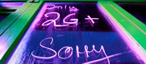 Auf der Scheibe eines Nacht-Lokals steht in bunter Schrift "Only 2 G+ - Sorry!"