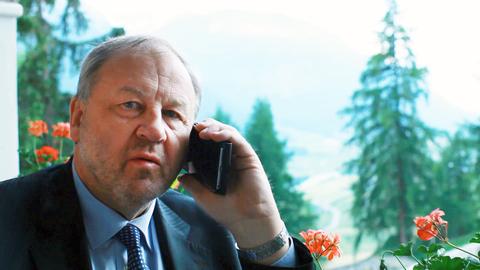 Portrait von Hanno Berger, der telefoniert und im Grünen oder auf einem Balkon sitzt.